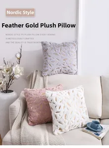 Detailed view of plush pillow covers with golden feather patterns on a sofa