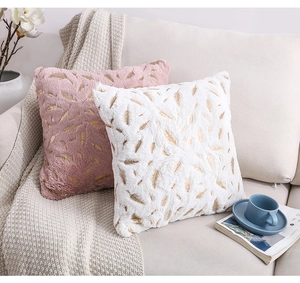 Close-up of plush pillow covers with gold feather pattern in a cozy home setting