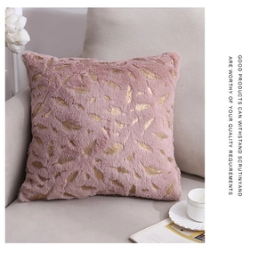 Detail of plush dusty pink pillow cover with gold foil feather pattern on a sofa