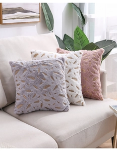 Macro detail of plush velvet pillow covers with golden feather patterns on sofa