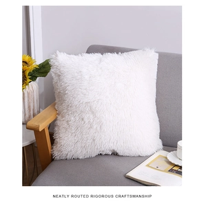 Detail of white long plush faux fur pillow cover on a modern sofa with soft texture