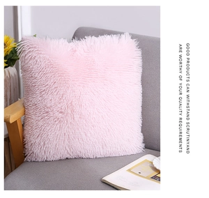 Close-up of soft pink faux fur throw pillow on a grey sofa in a cozy home setting