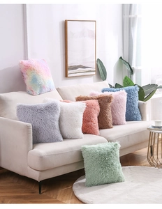 Close-up of fluffy faux fur pillow covers in various colors on a modern white sofa