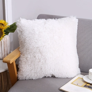 Soft white faux fur decorative pillow on a gray sofa with a cozy home setting