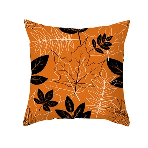 Square orange pillowcase with black and white maple leaf patterns on a white background