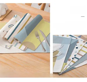 Detail of linen placemats with modern geometric patterns on a wooden dining table