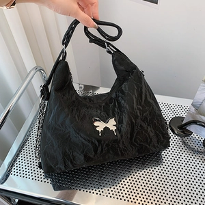 Black tote shoulder bag with glossy crinkle texture and silver butterfly ornament