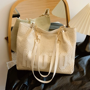 Minimalist straw tote bag with HOTO letter design and gold chain strap in a stylish setting