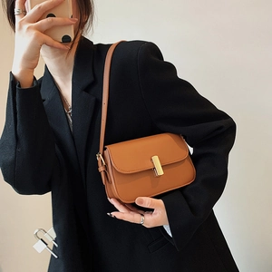 Vintage brown leather saddle bag with gold buckle on a model in a black blazer