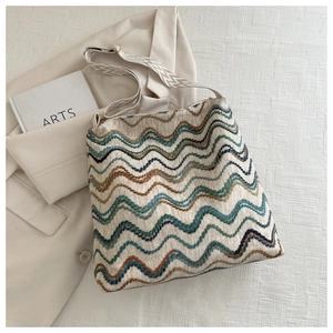 Detail of bohemian woven tote bag with blue wave patterns and patterned wide shoulder strap