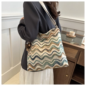 Mehrfarbige Strick-Tote-Bag mit Wellenmuster am Modell inklusive plüschigem Anhänger