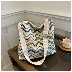 Detail of colorful wavy knit tote bag with geometric diamond patterned strap