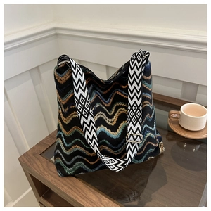 Detail of bohemian knitted tote bag with wavy patterns and geometric wide shoulder strap