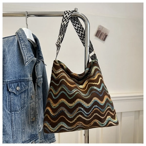 Dettaglio di borsa tote boho intrecciata con motivi a onde e tracolla geometrica