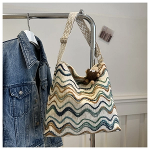 Dettaglio della borsa tote tessuta con ricami ondulati colorati e tracolla geometrica