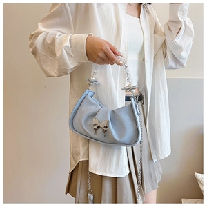 Detail of light blue pleated croissant bag featuring a silver butterfly buckle and beaded strap
