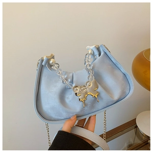 Détail du sac plissé bleu clair avec fermoir papillon doré et anse en perles chic
