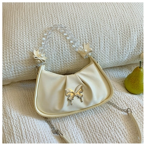 Détail du sac à main plissé crème avec papillon argenté et poignée en perles
