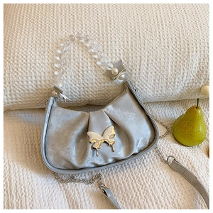Détail du sac à main plissé argenté avec poignée en perles et fermoir papillon