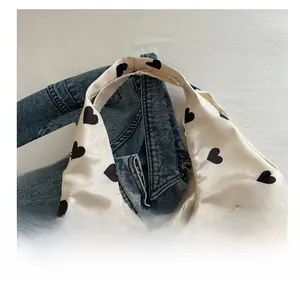 Close-up of white satin tote bag with black heart print and wide comfortable handle