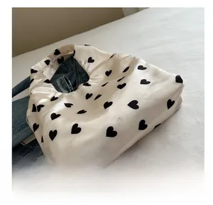 Detail shot of lightweight cream satin tote bag with black heart prints on denim jacket