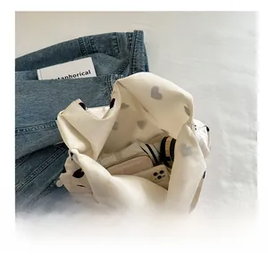 Detail view of the spacious white nylon bag interior showing heart prints and daily items