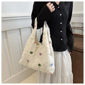 Detail of white tote bag featuring textured feather patterns and colorful dot embroidery