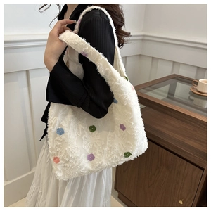 Close-up of white knitted tote bag with colorful 3D floral embroidery and wide strap