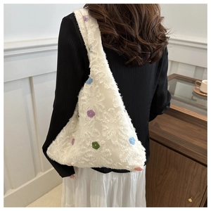 Close-up of white knit hobo bag with colorful floral embroidery and textured plush fabric