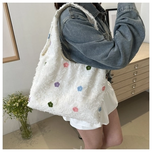 Detail of white textured tote bag with colorful floral embroidery and fringe