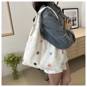 Detail of white knit tote bag with colorful 3D floral embroidery and soft texture
