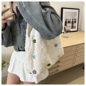 Detail of white plush tote bag featuring colorful floral embroidery and soft texture