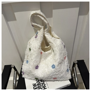 Detailed view of floral embroidery on a soft plush white tote bag with colorful petals