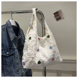 Detail of white plush tote bag with multi-colored embroidered flowers and soft texture