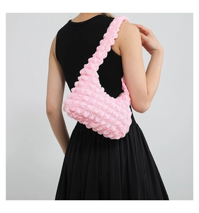 Détail du sac à bandoulière rose à texture popcorn plissée porté par le modèle