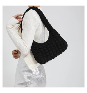 Gros plan sur la texture gaufrée noire et les détails plissés du sac à bandoulière