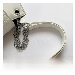 Detail of white crocodile embossed texture handbag with silver chain and wide strap