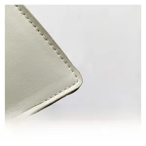 Detailed macro view of white leather texture and neat stitching on a chain shoulder bag