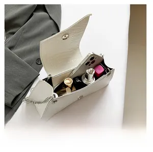 Detailed interior view of white crocodile pattern bag showing capacity for phone and makeup
