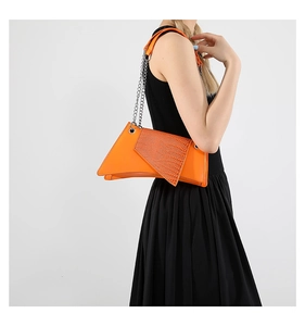 Orange geometric crossbody bag with crocodile embossed flap shown on model with black dress