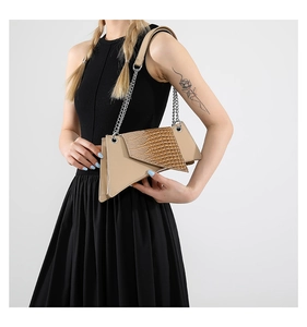 Detail of beige crocodile embossed asymmetric bag with stylish silver chain strap