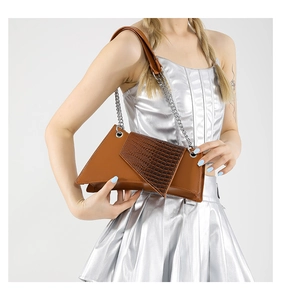 Detail view of asymmetric geometric crossbody bag with brown faux croc texture