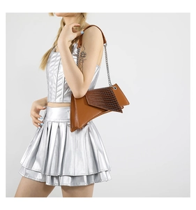 Detail of asymmetrical brown crocodile pattern shoulder bag with silver chain strap
