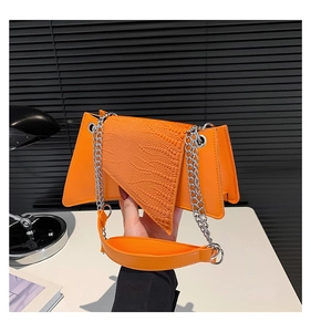 Detail of orange crocodile pattern crossbody bag with unique triangular flap design