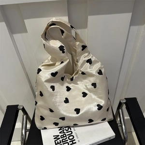 Minimalist knit tote bag with black heart patterns on cream satin fabric, stylish shoulder bag