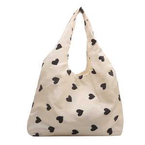 Minimalist cream knit tote bag featuring an all-over black heart pattern print