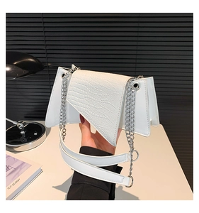 Detail of white crocodile pattern flap on geometric chain bag with silver hardware