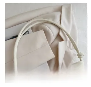 Détail du sac seau en cuir crème avec boucle papillon en métal et bandoulière nouée