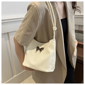 Détail du sac à bandoulière crème avec ornement papillon et bandoulière nouée