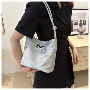 Sac à épaule argenté avec boucle papillon porté par un mannequin dans un décor chic